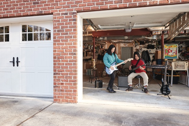 Teens playing musical instruments in a garage with the doors open