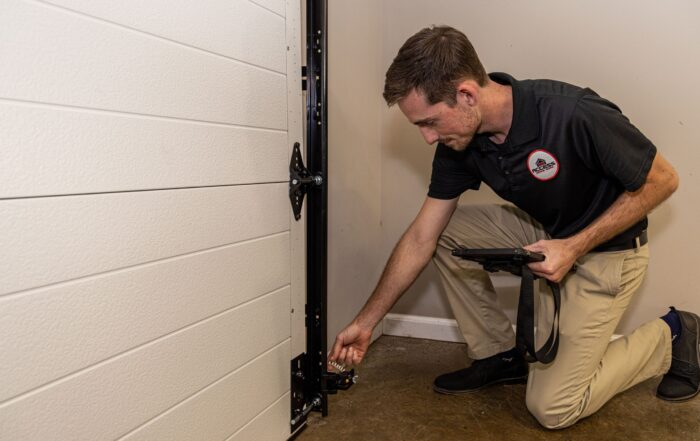 Specialist checking the garage door sensor near the bottom.