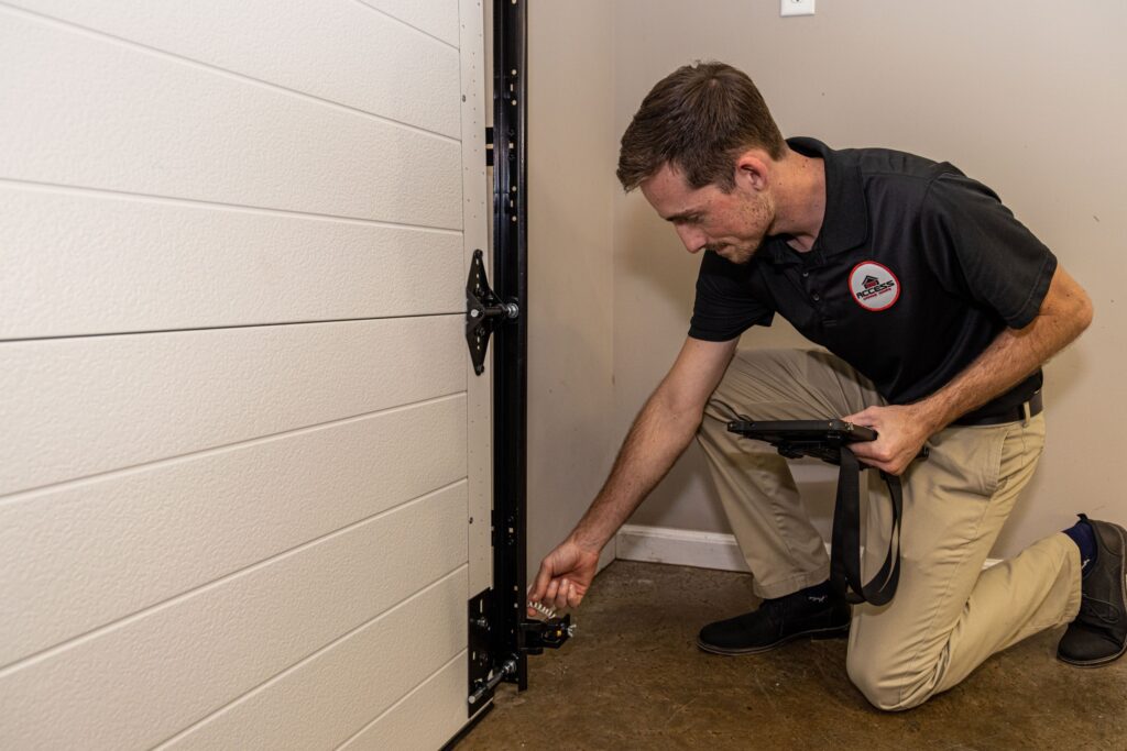 Specialist checking the garage door sensor near the bottom.