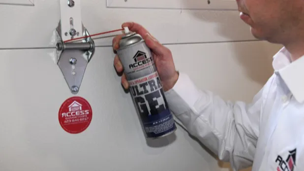 Access Garage Doors employee spraying lubricant on garage door hinges