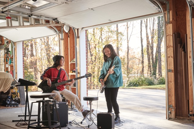 Teens playing music in a garage with the door open